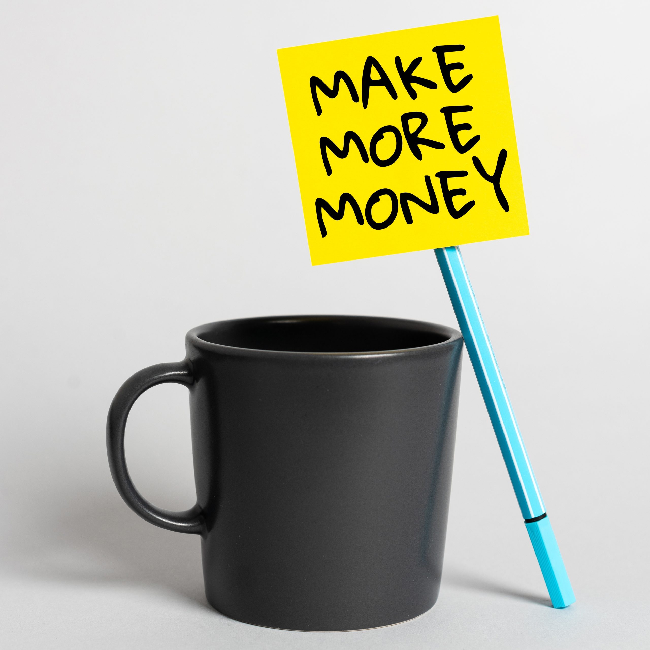 Image of a coffee cup with a pen and post-it note that says Make More Money